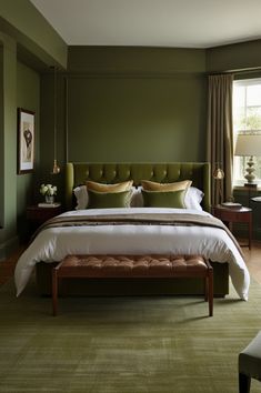 a bedroom with green walls and a bed in the middle, along with an ottoman