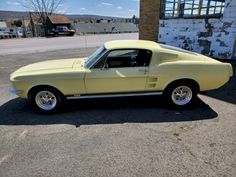 an old yellow mustang sitting in a parking lot