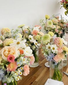 several vases filled with different types of flowers on a wooden table next to each other