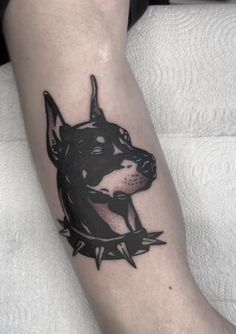 a black and grey dog tattoo on the leg with an arrow around it's neck