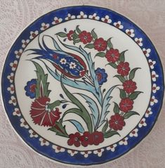 a blue and white plate with red flowers on the rim, sitting on a table