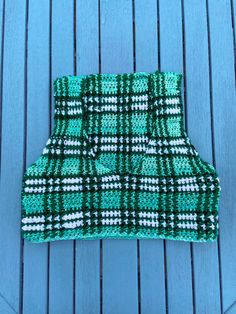 a green and white knitted dishcloth sitting on top of a blue wooden table