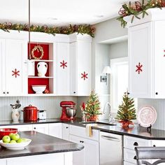 a kitchen with white cabinets and christmas decorations on the counter top, is featured in this article