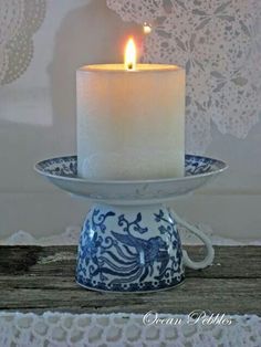 a lit candle sitting on top of a blue and white plate next to a lace doily