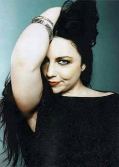 a woman with her arm around her head and wearing bracelets, posing for the camera