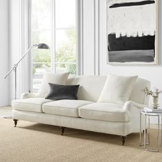 a living room with white couches and black and white art on the wall above them