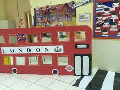 a double decker bus made out of cardboard in a school hallway with decorations on the wall