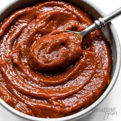 a metal bowl filled with sauce and a spoon