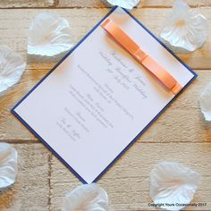 an orange ribbon is on top of a wedding card with seashells around it