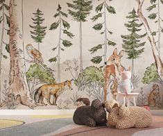 two stuffed animals sitting on the floor in front of a forest wallpapered mural