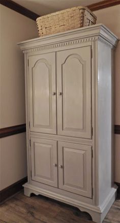 a white armoire with a basket on top