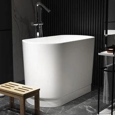 a white bath tub sitting in a bathroom next to a wooden stool and black wall