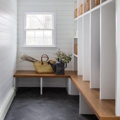 an empty room with white walls and wood flooring, along with shelves filled with plants