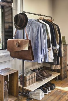 an open closet with clothes and shoes hanging on the rack, next to a window