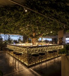 an outdoor bar is lit up at night with lights shining on the tables and chairs