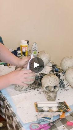 a woman sitting at a table with skulls and other crafting supplies on top of it