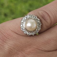 This is a unique 14k yellow gold vintage ring that is featuring an off white round pearl and surrounded with diamonds. This is a vintage ballerina style art Nouveau ring. The pearl is glued in as is customary for this style and age and the diamonds are prong. there are 14 bright white in color single cut diamonds. This ring is currently a US size 6 but can be resized to accommodate most sizes. If you need a sizing please reach out to us before your purchase so we can have our jeweler review the setting to verify that size can be accommodated.  Just the facts Vintage Ring 14k Yellow Gold Off White Pearl 14 Vintage Single Cut Diamonds approx .85cttw H color VS clarity Us Size 6 3.9dwt/6.1grams ~~free shipping in the US, International rates do apply~~ Antique White Pearl Ring Hallmarked, 1920s Jewelry, Vintage Ballerina, Art Nouveau Ring, Ballerina Style, Filigree Pendant, Ring Vintage, 14k Gold Ring, Pearl White