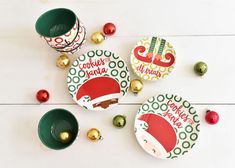 three plates with santa's hats on them next to christmas ornaments