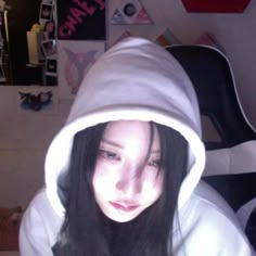 a woman with long black hair wearing a white hoodie and looking at the camera