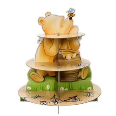 a three tiered cake stand with a bear and bee design on the top, holding a honey pot