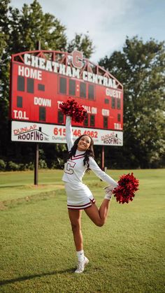 a cheerleader is posing in front of the scoreboard with her pom poms