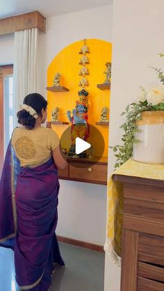 a woman in a purple sari is looking at some vases on the wall