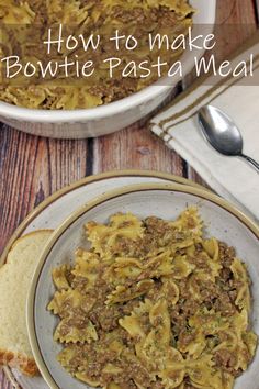 a bowl filled with pasta and meat on top of a wooden table next to bread