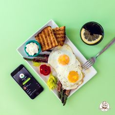 a plate with eggs, asparagus and toast on it next to a cell phone