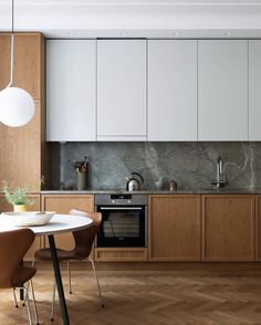 a kitchen with wooden flooring and white cabinetry next to a dining room table