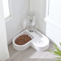 a water dispenser with coffee beans in it next to a cat bowl