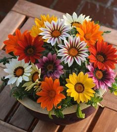 a bunch of flowers that are in a vase on a table and sitting on a bench