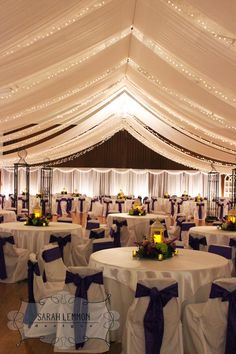 a banquet hall with tables and chairs covered in white linens, purple sashes and lights