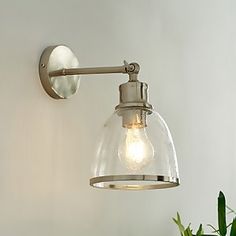 a light that is on the side of a wall next to a potted plant