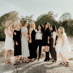 a group of women standing next to each other on top of a rocky hill with trees in the background