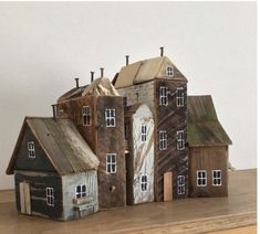 a group of wooden houses sitting on top of a table next to each other in front of a white wall