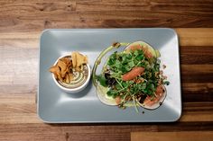 a white plate topped with two tacos covered in veggies and toppings