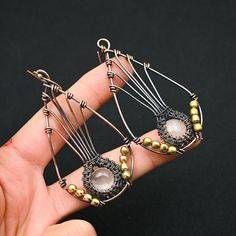 a pair of earrings is being held in someone's hand with beads on it