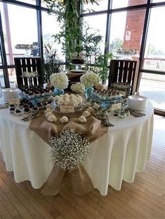 the table is set up for an event with flowers and desserts on it,