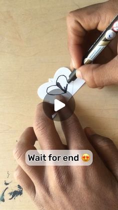 someone is cutting out a heart with a crayon pen on a wooden table