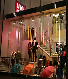 people are walking up and down the stairs in front of an umbrella store at night