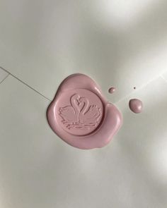 a wax stamp with two swans on it and water drops around the stamp, which is shaped like a heart