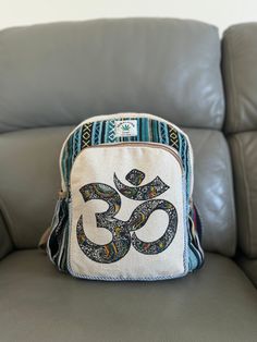 a small bag sitting on top of a gray leather couch next to a black and white pillow