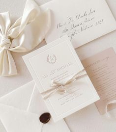 the wedding stationery is laid out on top of an envelope with a white ribbon