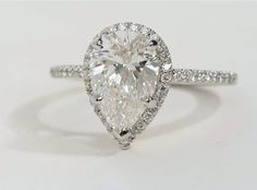 a pear shaped diamond ring with pave set shoulders