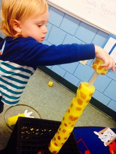 a little boy is playing with some sort of thing in the room that looks like a giraffe