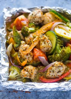 chicken and veggies in a foil container with seasoning sprinkled on top