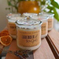 several candles sitting on top of a wooden table next to oranges and lavender sprigs