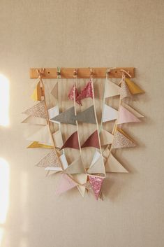 a wall hanging made out of different colored paper triangles and ribbons on a wooden frame