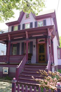 a pink and purple house with stairs leading up to the front door