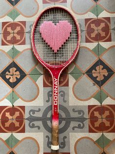 a red tennis racquet with a pink heart on it's back end